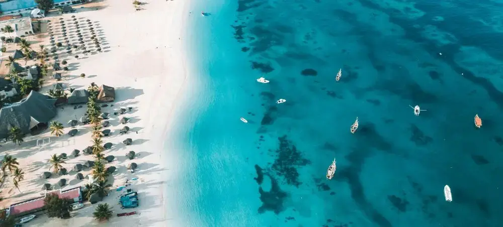 Aerial view of pristine Tanzanian coastline with turquoise waters, white sand beach, and luxury yachts