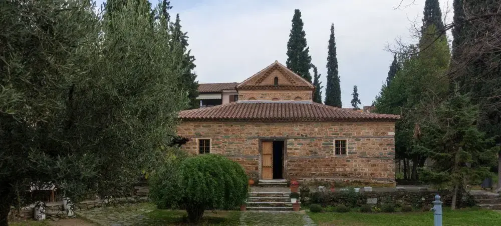 Traditional Byzantine stone church with terracotta roof surrounded by cypress trees in Thessaloniki Greece