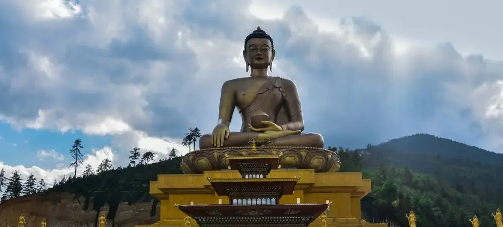 Majestic Buddha Dordenma statue overlooking Thimphu valley with forested mountains under dramatic sky