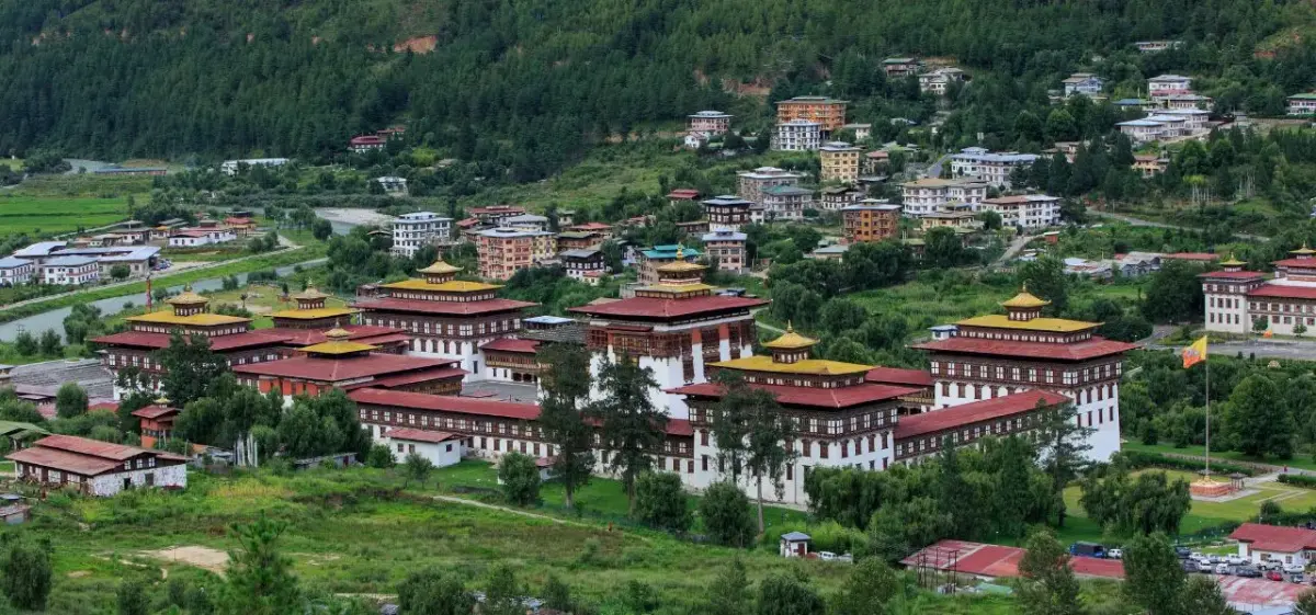 Panoramic view of Thimphu's traditional dzong fortress and modern buildings nestled in Bhutan's green valley