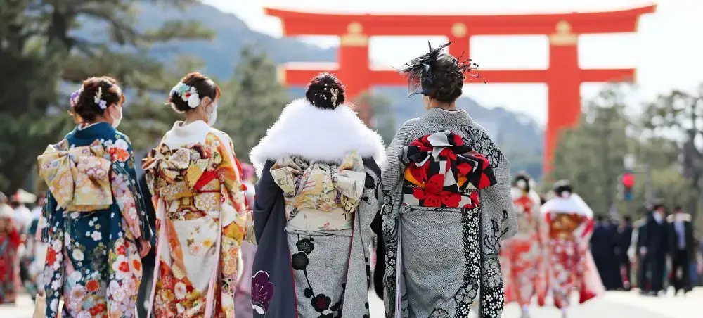 Women in traditional kimono celebrating at Japanese shrine with iconic red torii gate in Tokyo