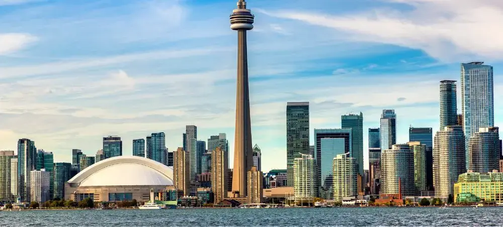 Toronto skyline featuring CN Tower and Rogers Centre viewed from Lake Ontario waterfront on sunny day