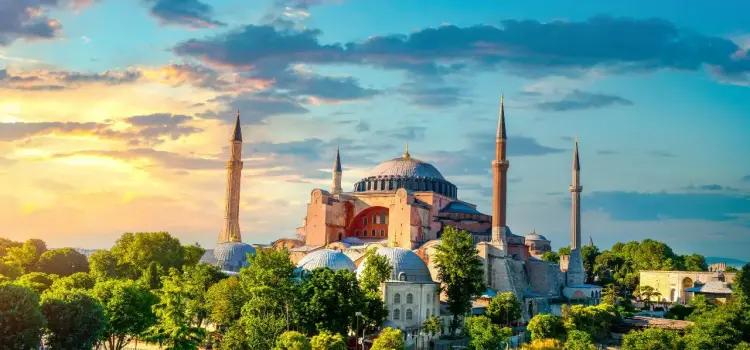 Hagia Sophia's iconic dome and minarets rising above Istanbul's skyline at golden hour sunset