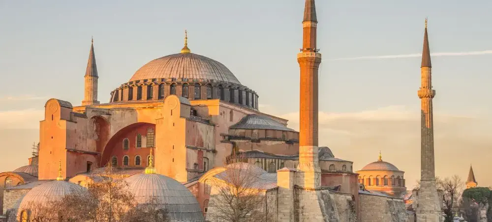 Hagia Sophia's iconic dome and minarets illuminated by golden sunset light in Istanbul, Turkey