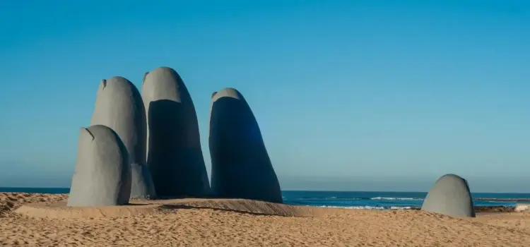 Iconic hand sculpture emerging from Punta del Este beach in Uruguay under clear blue sky