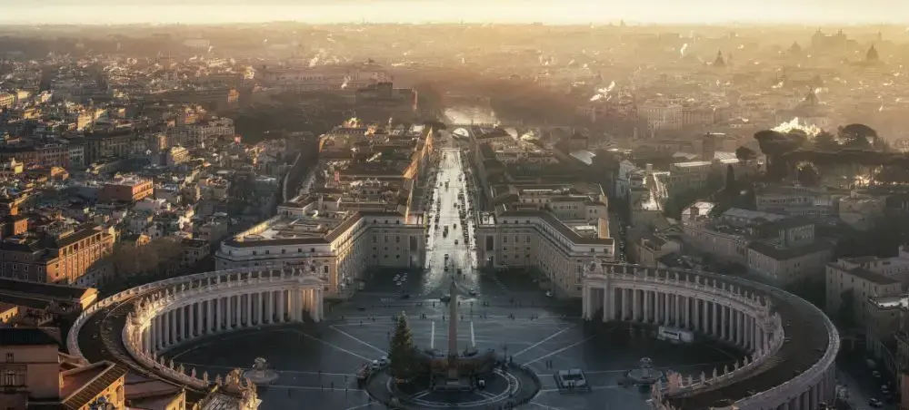 Aerial view of Vatican City's St. Peter's Square at golden hour, showcasing Rome's iconic architecture