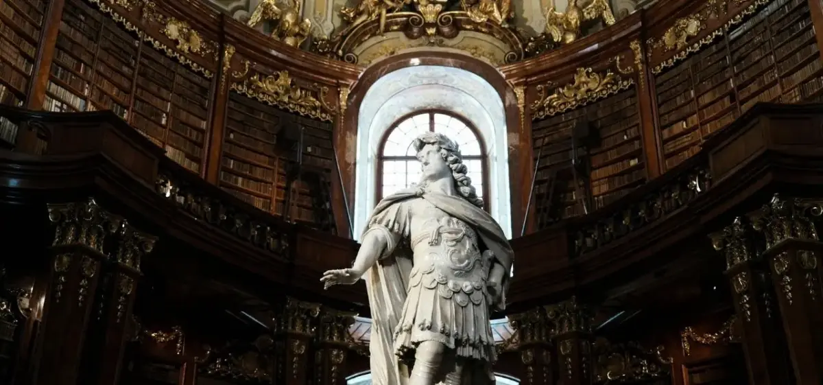 Ornate baroque library interior with classical statue and gilded details in historic Vienna cultural institution