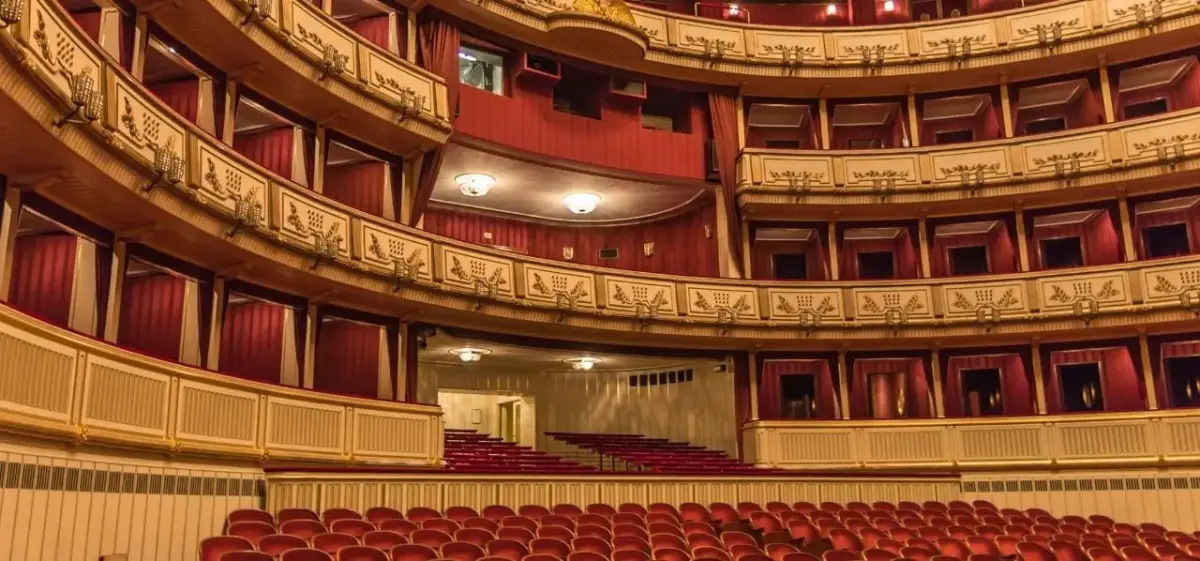 Ornate Vienna opera house interior with red velvet seats and golden baroque balconies showcasing Austrian cultural heritage