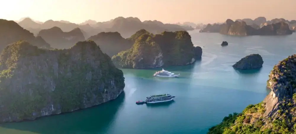 Luxury cruise ships navigate emerald waters between towering limestone karsts in Vietnam's Ha Long Bay