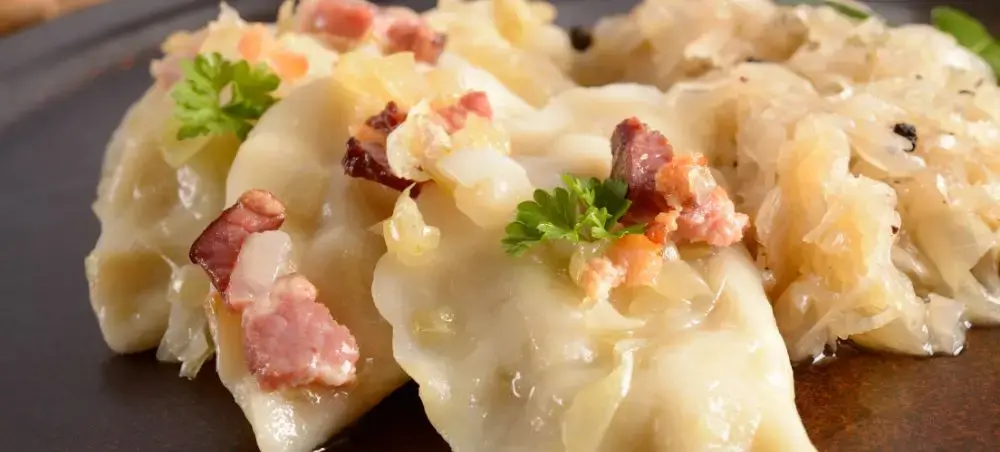 Traditional Polish pierogi dumplings with bacon and herbs served on slate plate in Warsaw restaurant