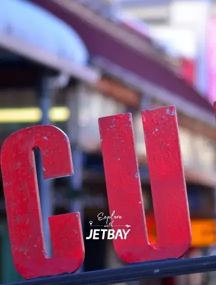 Red CU letters at Wellington's iconic Cuba Street with blurred cityscape showcasing New Zealand's capital