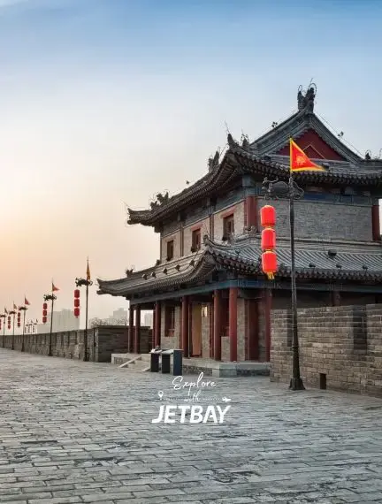 Ancient Xi'an city wall fortifications with traditional Chinese architecture and red lanterns at sunset