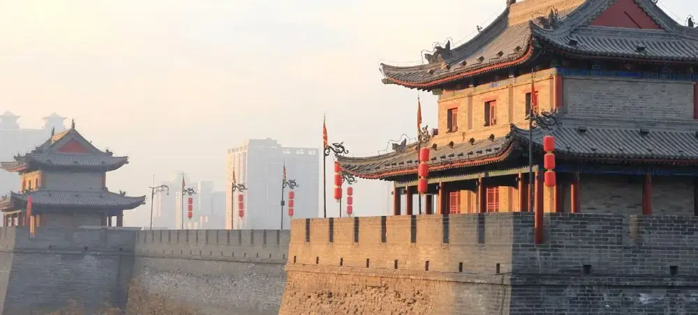 Ancient Xi'an city wall fortifications with traditional Chinese architecture and red lanterns at sunset