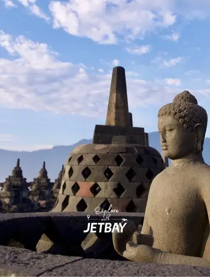 Ancient Buddha statue and perforated stone stupa at Borobudur temple complex in Yogyakarta, Indonesia