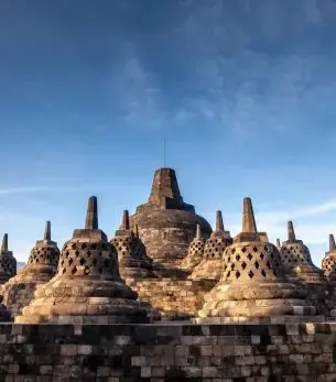 Ancient Borobudur temple complex with intricate stone stupas under clear blue sky in Yogyakarta Indonesia