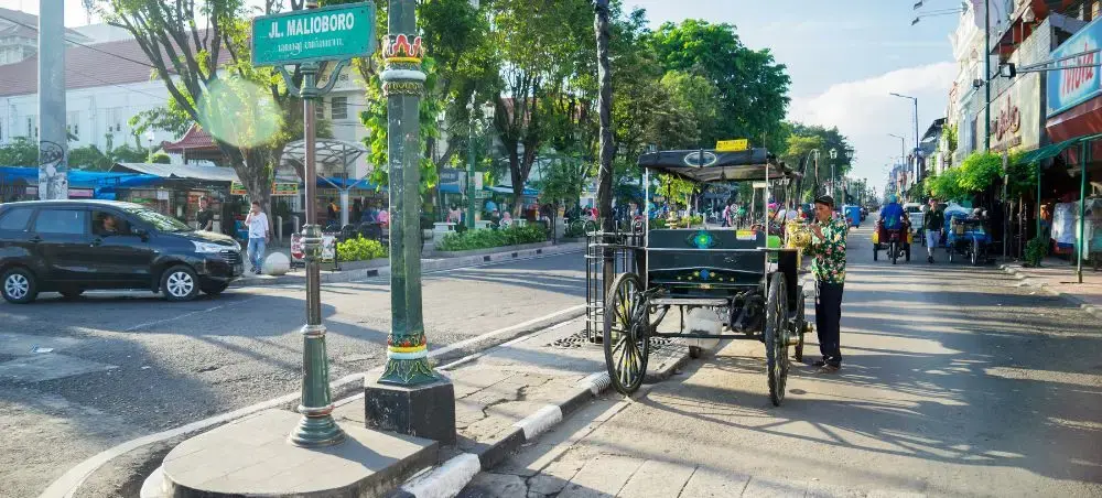 Bustling Malioboro Street in Yogyakarta with traditional horse-drawn carriages and local traffic