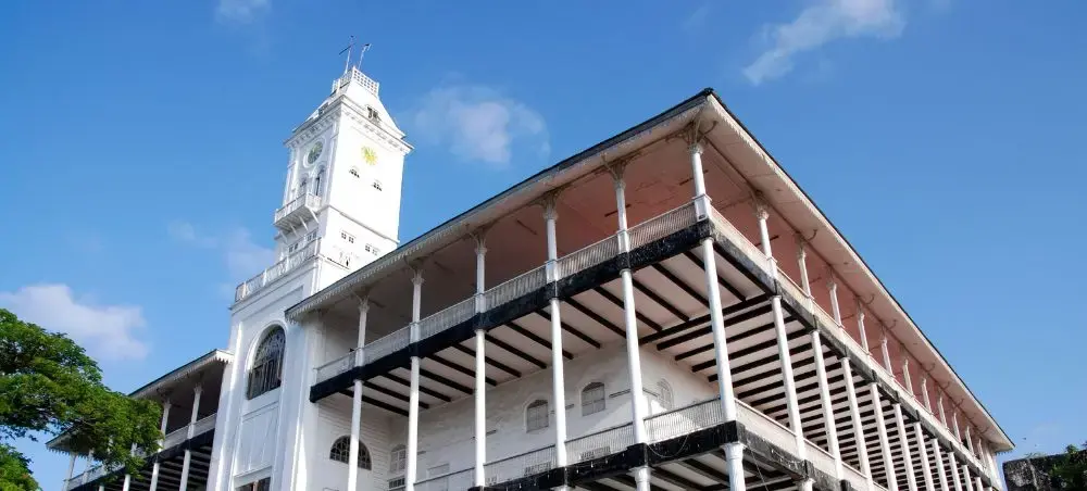 Historic colonial architecture with white clock tower and red brick building in Stone Town, Zanzibar