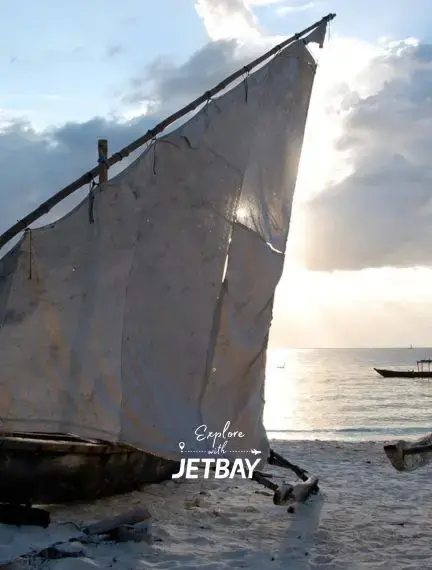 Traditional dhow sailing boat on pristine Zanzibar beach at sunset with calm Indian Ocean waters