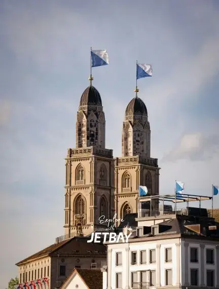 Historic Grossmünster cathedral towers with Swiss flags overlooking Zurich's charming old town architecture