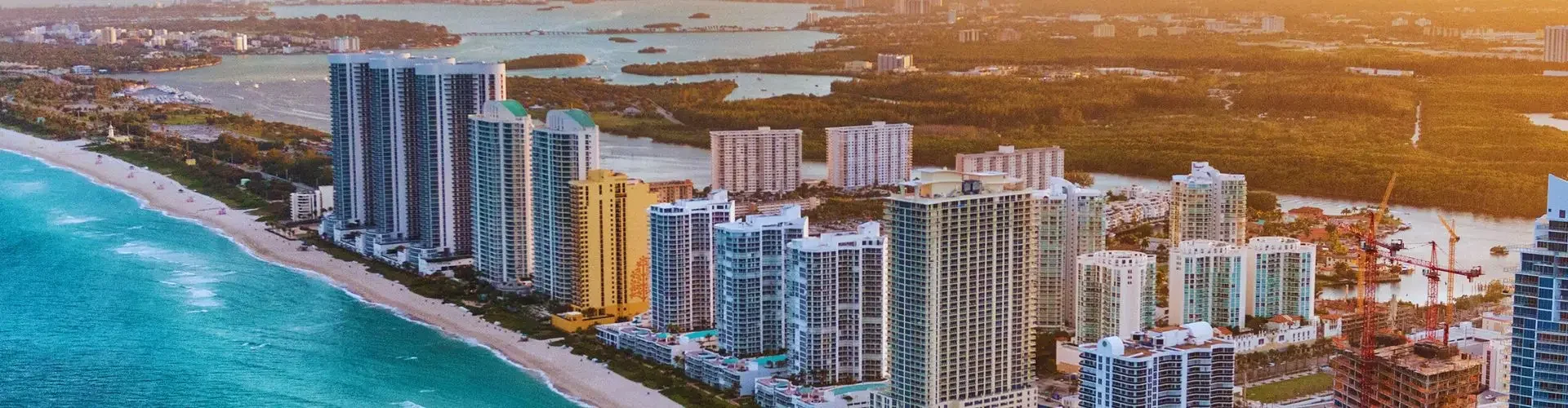 Private Jet Charters from Miami-Opa Locka Executive Airport (OPF) Miami Beach skyline with luxury high-rise buildings along turquoise coastline at golden sunset