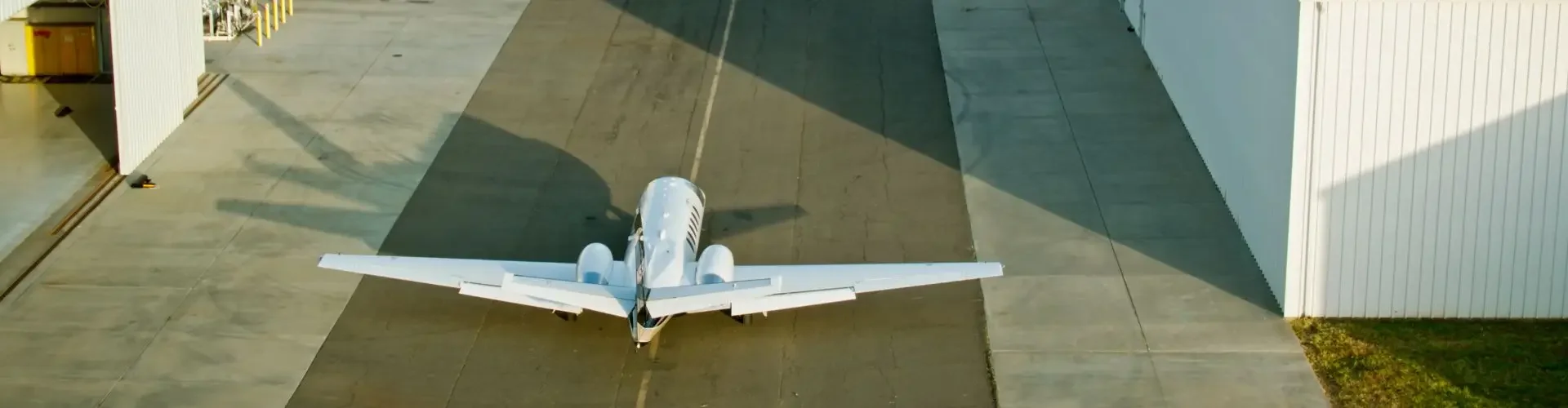 White medical aircraft positioned on airport tarmac between hangars ready for emergency transport flight