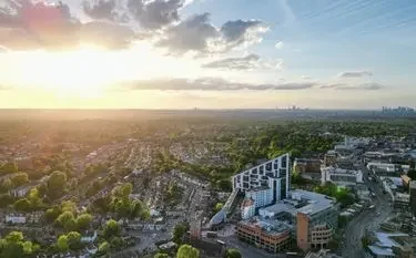 Aerial view of suburban London neighborhoods at golden hour with distant city skyline visible