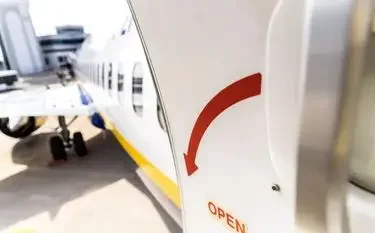 Aircraft door with red emergency handle open at airport, ready for urgent medical charter flight departure