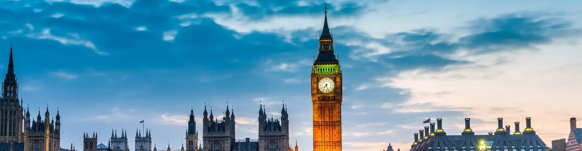 Westminster Bridge and Big Ben illuminated at dusk reflecting in Thames River for UK private jet charter