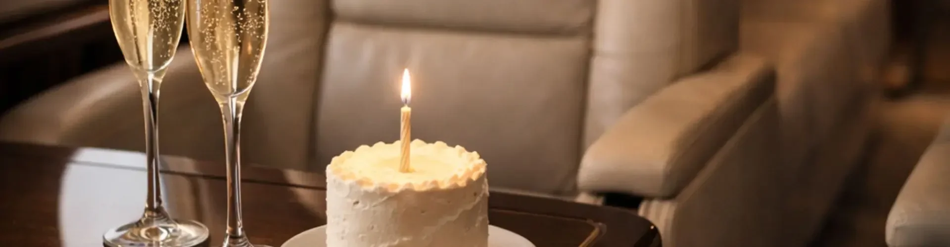 Champagne with flutes for a birthday cake lit candle private jet table luxury leather seating