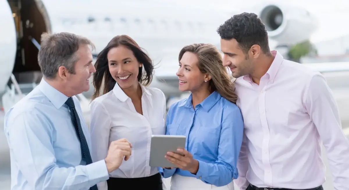 Business professionals collaborating with tablet near private jet, showcasing seamless corporate travel