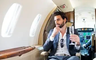 Businessman enjoying champagne in luxurious private jet cabin with panoramic windows and premium seating