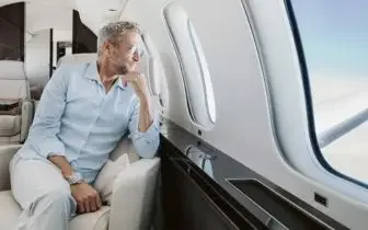 Businessman relaxing in luxury private jet cabin while considering UK charter costs and premium travel options