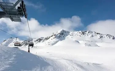 Cable car ascending snow-covered Alpine slopes with dramatic mountain peaks in St. Moritz ski resort