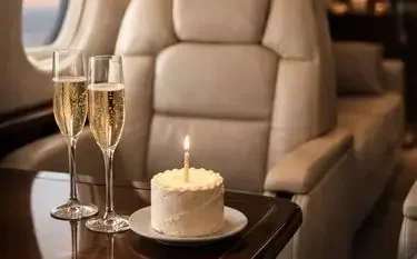 Champagne with flutes for a birthday cake lit candle private jet table luxury leather seating