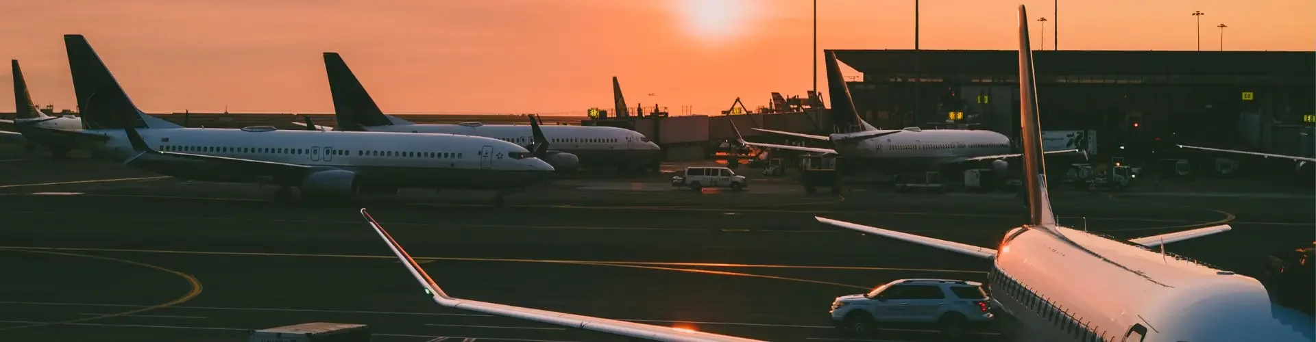 Navigating Airport Operating Hours with Jetbay Commercial aircraft parked at airport terminal during golden sunset with warm orange sky and ground equipment