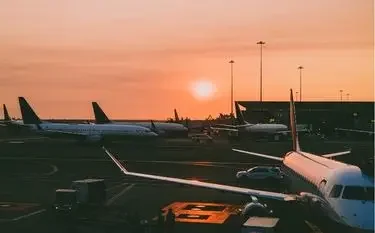 Navigating Airport Operating Hours with Jetbay Commercial aircraft parked at airport terminal during golden sunset with warm orange sky and ground equipment