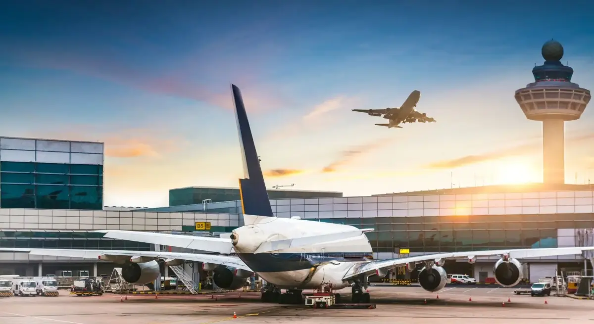 Commercial aircraft at Singapore Changi Airport terminal with control tower during golden hour sunset