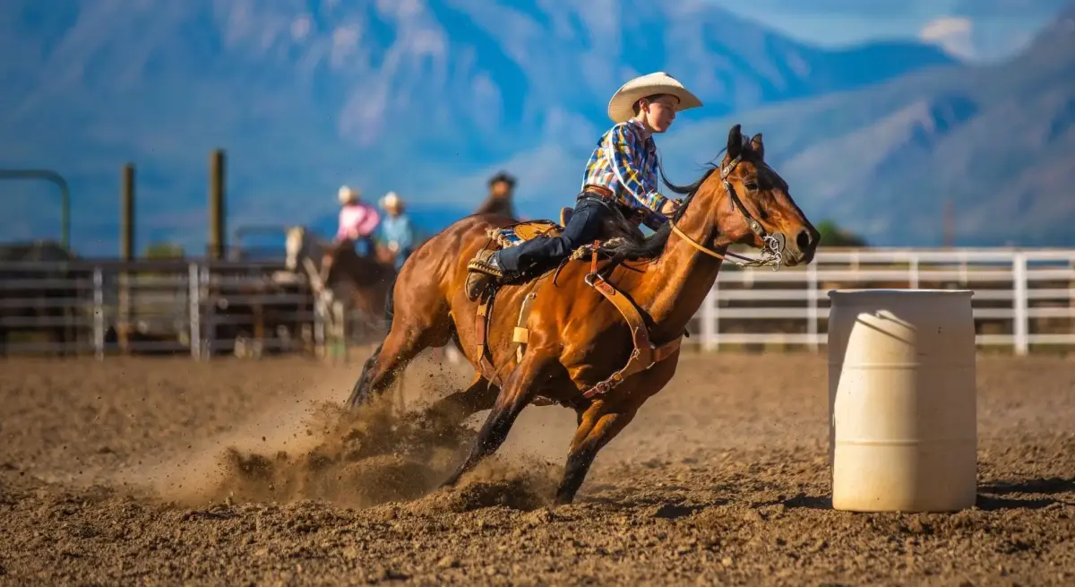 Cowboy rider navigating barrel racing course at mountain rodeo arena, showcasing western events accessible by private jet