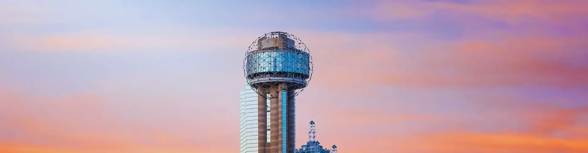 Dallas skyline with Reunion Tower at sunset showcasing vibrant orange and pink skies over downtown