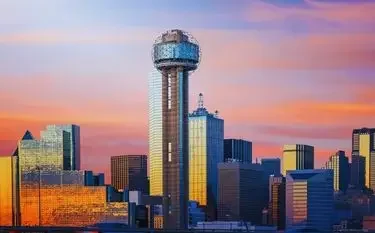 Dallas skyline with Reunion Tower at sunset showcasing vibrant orange and pink skies over downtown