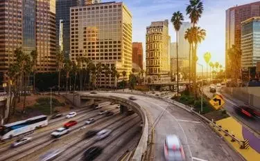 Downtown Los Angeles skyline at sunset with busy freeway traffic and palm trees for VNY private jet charter