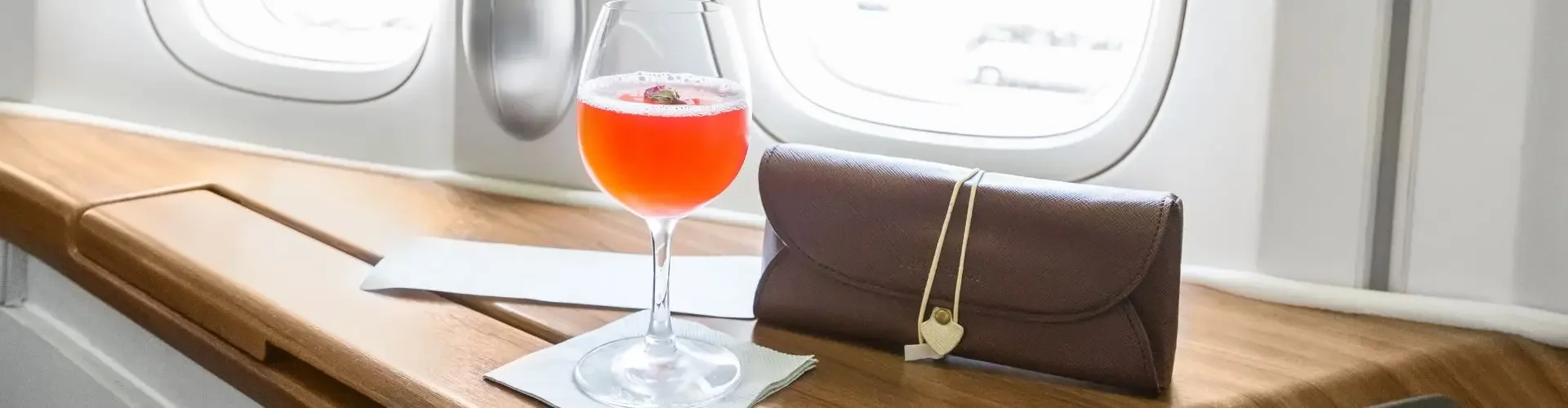 Elegant private jet cabin interior with wine glass, orchid, and leather accessories on polished wood table