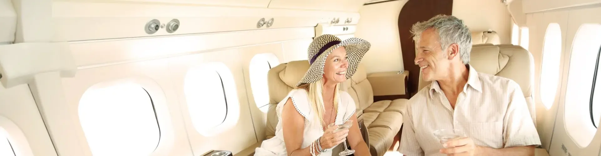 Elegant couple enjoying spacious luxury seating and panoramic windows aboard premium private jet cabin