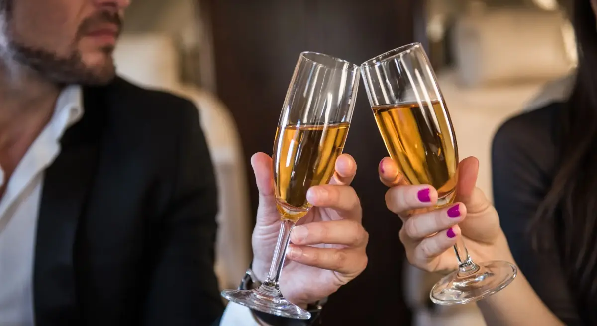 Elegant couple toasting with champagne flutes aboard luxury private jet, celebrating premium travel experience