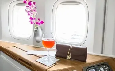 Elegant private jet cabin interior with wine glass, orchid, and leather accessories on polished wood table