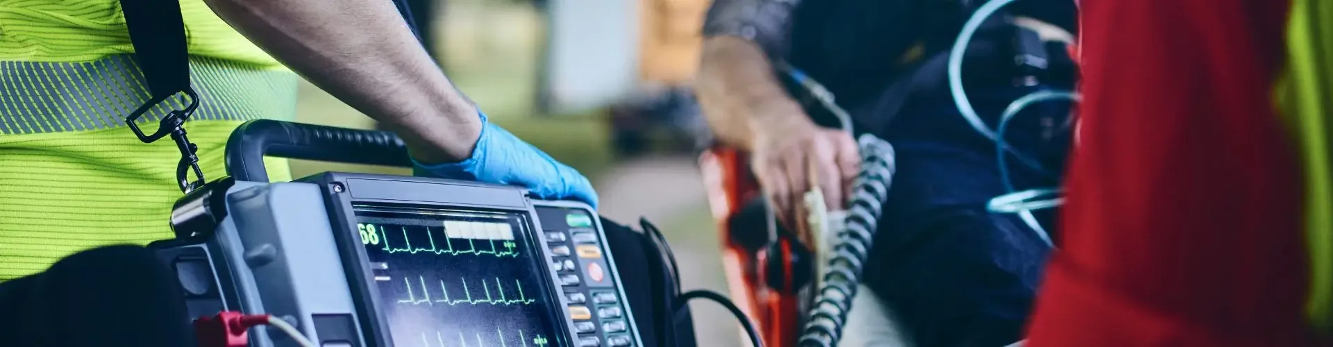 US Bed-to-Bed Transfer Explained Emergency medical technician operating portable defibrillator during critical patient transport procedure