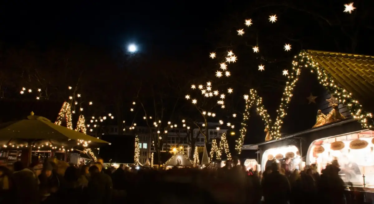 Enchanting Christmas market glowing with festive lights and holiday crowds beneath starlit evening sky