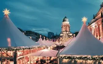 Festive Christmas market with illuminated white tents and historic architecture creating magical winter atmosphere