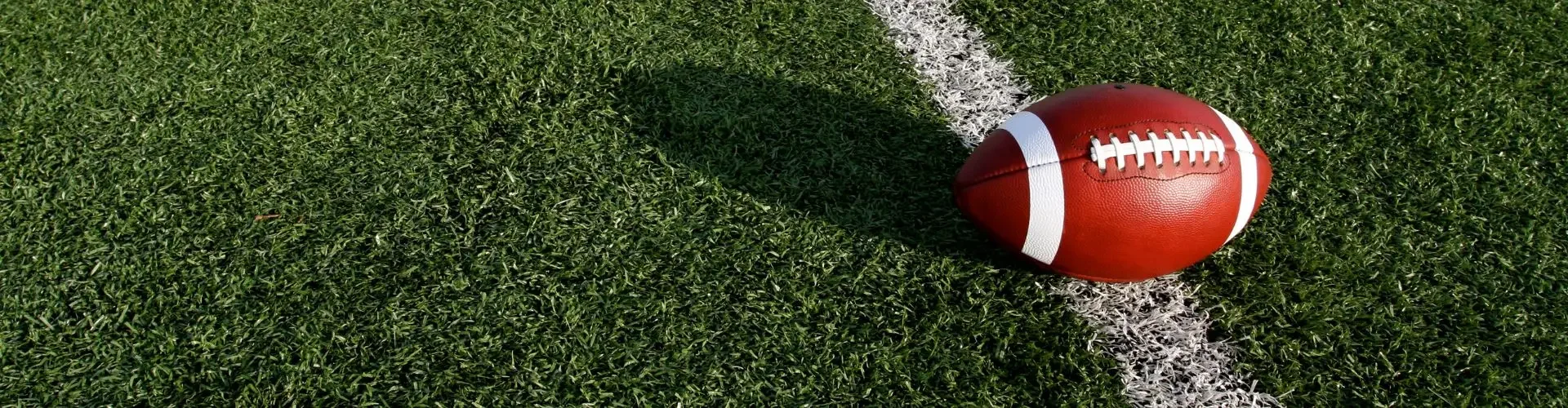 Football positioned on 20-yard line of professional stadium field for Super Bowl 2026 private jet travel