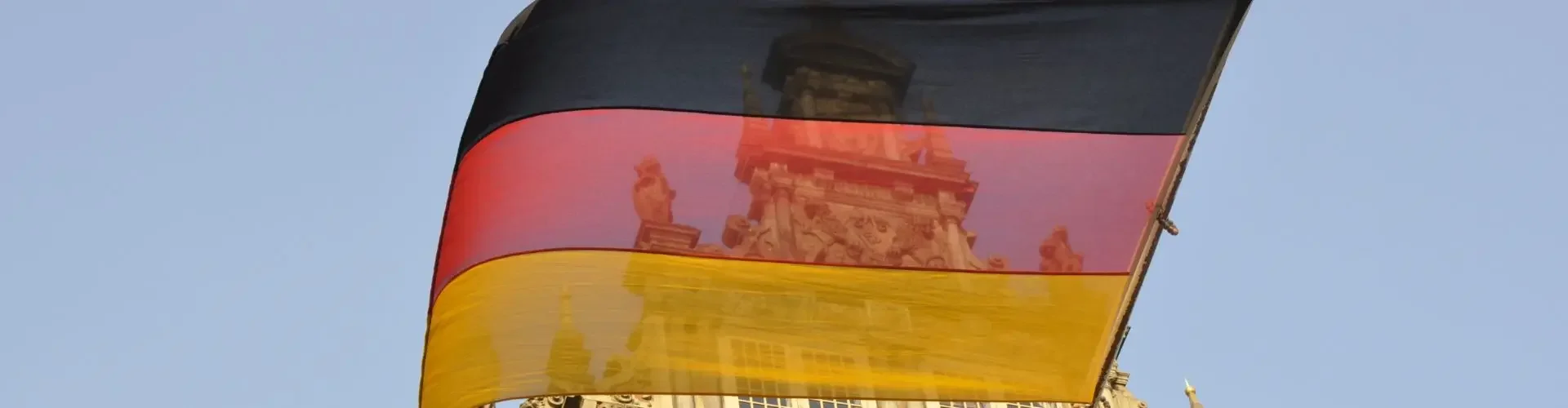German flag waving above ornate baroque architecture representing luxury travel destinations in Germany